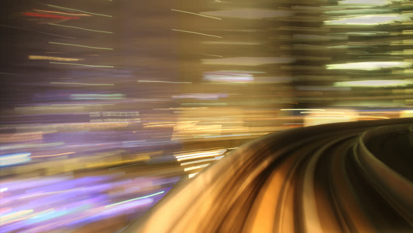 Commuter train traveling from left to right across frame, large building in background
