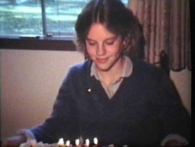 A cute teenage girl blows out the candles on her birthday cake several times. 