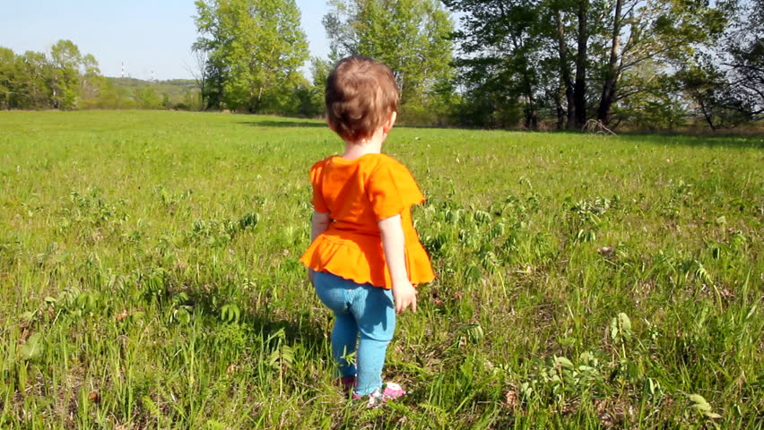 Baby first steps on green lawn