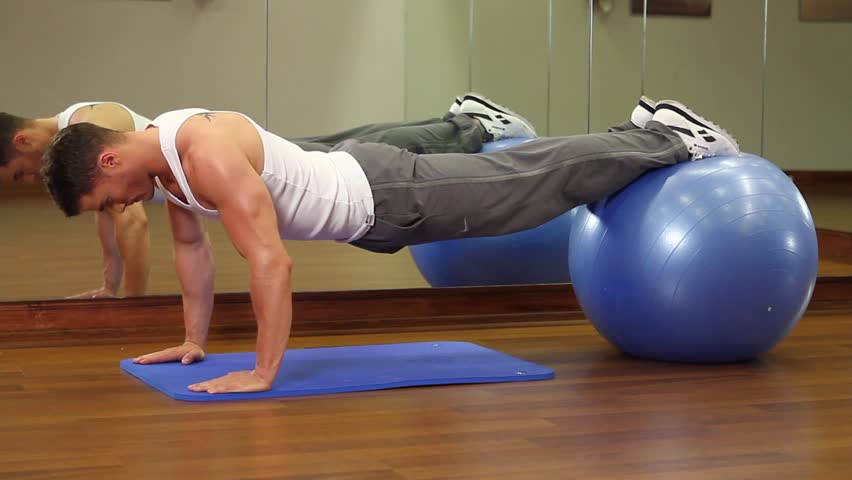 Handsome sporty man is exercising in gym centre