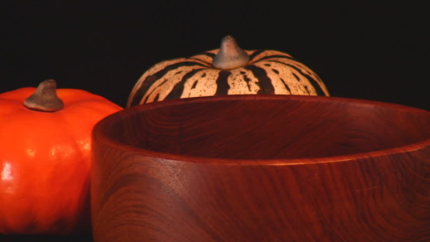 Traditional Halloween candy corn poured into wooden bowl against black background plus slow motion -HD