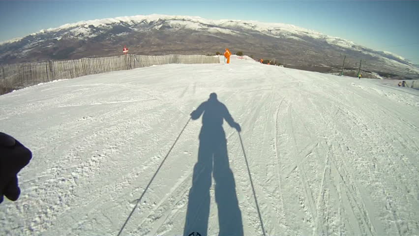 Silhouette of man skiing down slope