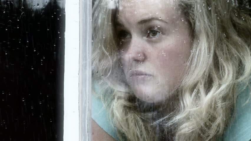 Girl looking out of a window a rainy day.