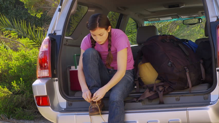 Young woman lacing up boots  for a hike