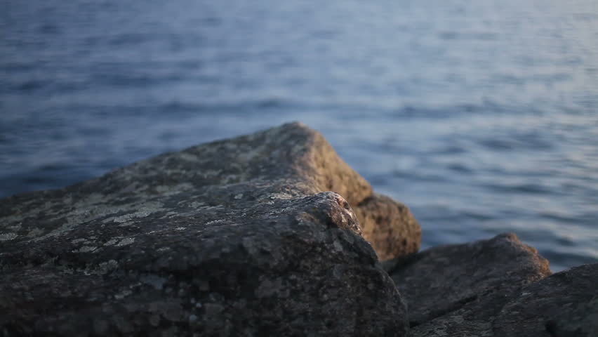Beautiful barefoot girl jumping on the stones by the sea