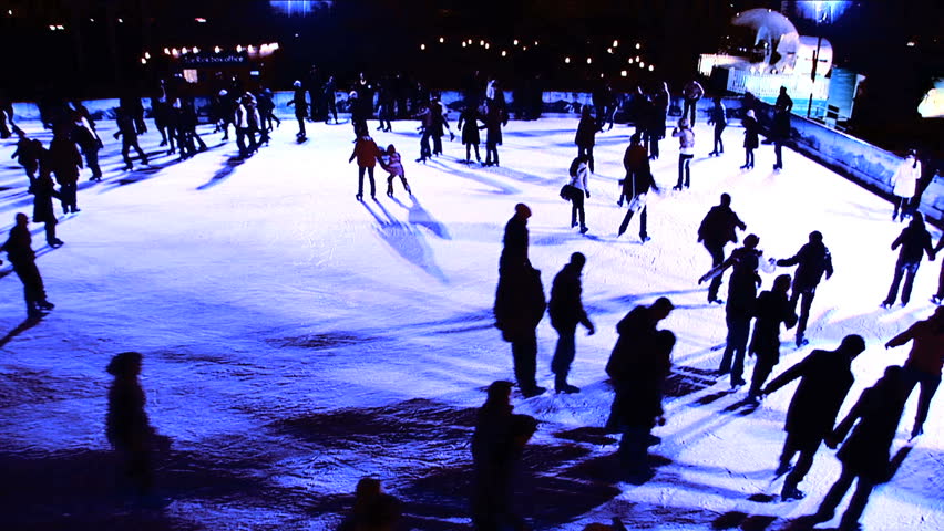 Winter outdoor ice skating with crowds of people in silhouette