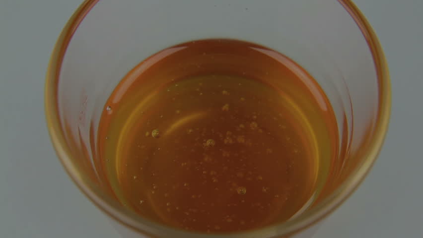 Honey twirler is dipped into a glass of honey.