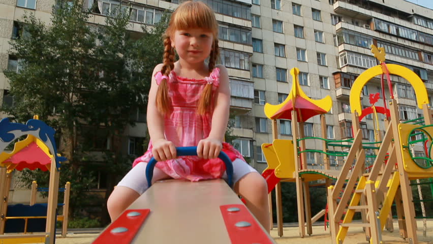 Little girl on seesaw looking at camera