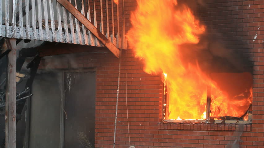 House burning in intense flames through window. Basement brick wall and patio in full flames and smoke. Total loss and destruction.