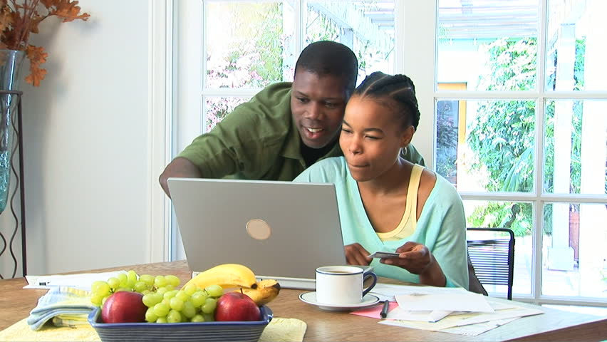 Young African American couple using credit card on laptop