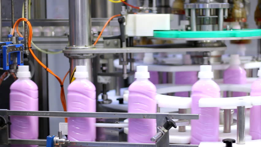 Bottle filling machine.Bottles of fabric softener moving along a conveyor belt.