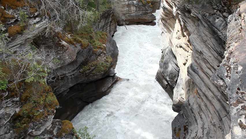 River valley gorge and river Maligne Canyon, Banff National Park, Alberta, Canada. Rushing water pours through narrow gorge created by forces of water. Popular vacation and naturalist destination.