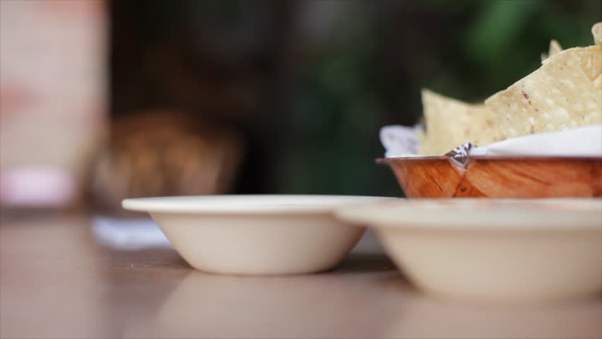 Close up of a womanÃÂ¯ÃÂ¿ÃÂ½s hand holding a crisp tortilla chip and dipping into some salsa verde.
