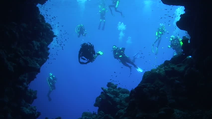 Group of scuba divers entering an underwater cave. Red Sea, Egypt.