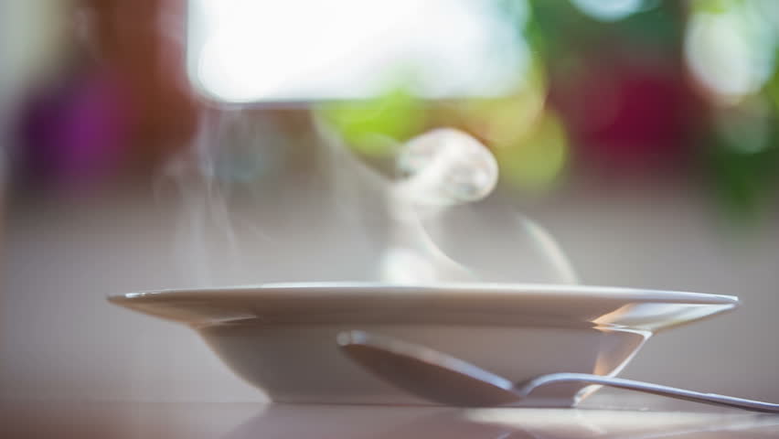 Kitchen Table Close Up a lot of steam from soup plate.close up shot with sun shining Kitchen Table Close Up a lot of steam from soup plate.close up shot with sun shining