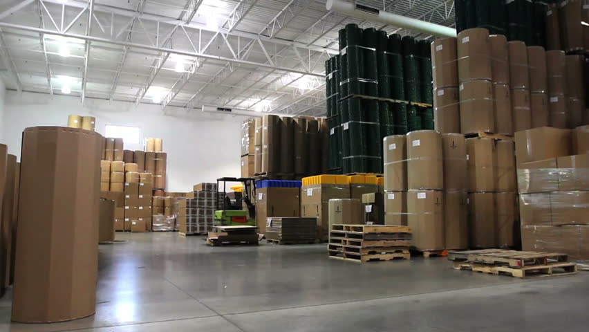 A forklift driver cruises through a large factory warehouse. 