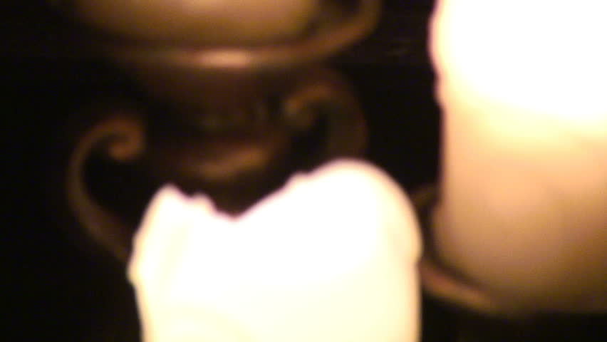 Camera pans from some candles in the foerground to the fireplace. Candles are intentionally out of focus. With ambient sound