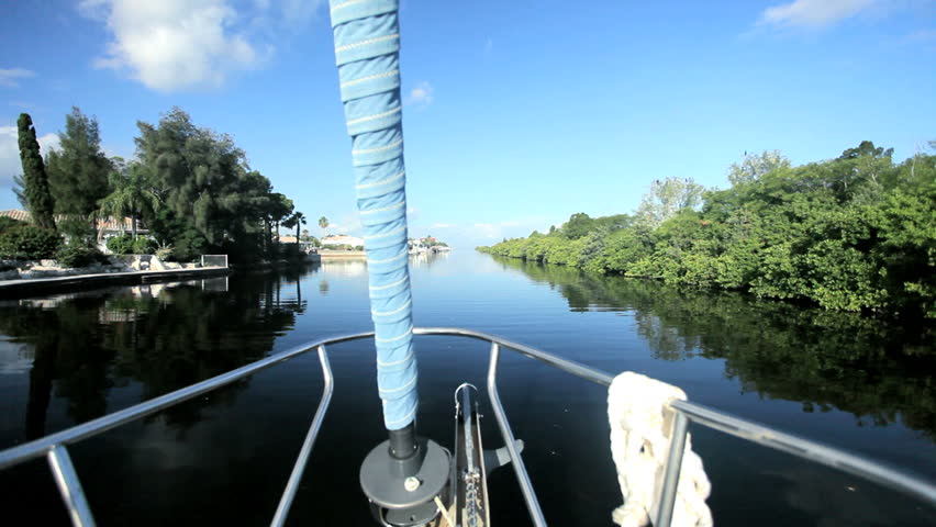 Bow of a luxury yacht sailing on waterways past luxury homes on a beautiful day