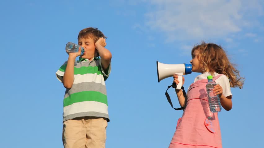 girl laughing through megaphone, boy drinking water and plugging up ear