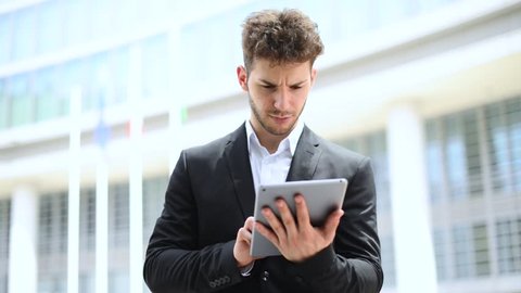 Мужчина управляет компьютером. Мужчина в костюме держит планшет. Деловая беседа. Проект в шаирпоинт. Picking the right medium.