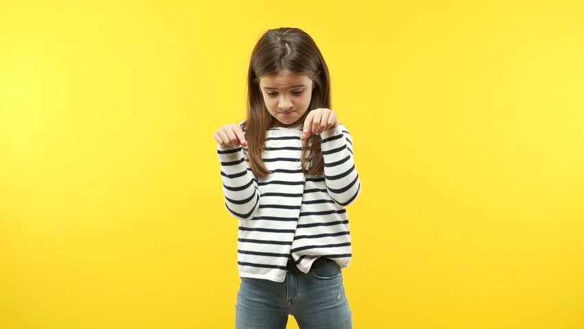 Funny child girl against an orange background pointing down ...