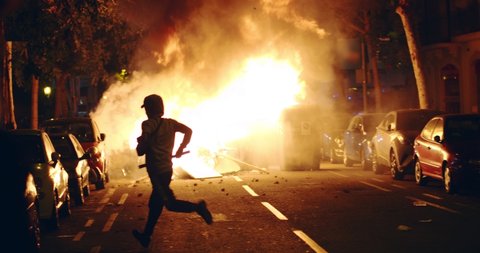 Young rebel riot revolutionary anarchist stands on trash and fire showing  fuck as protest for independence on demonstration about the proces and  political prisoners demonstrator burns garbage bins in