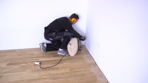 Scraping Floor Surface With Grinding Machine Repair In The Apartment Carpenter Grinder Parquet In A Narrow Corner With A Small Machine