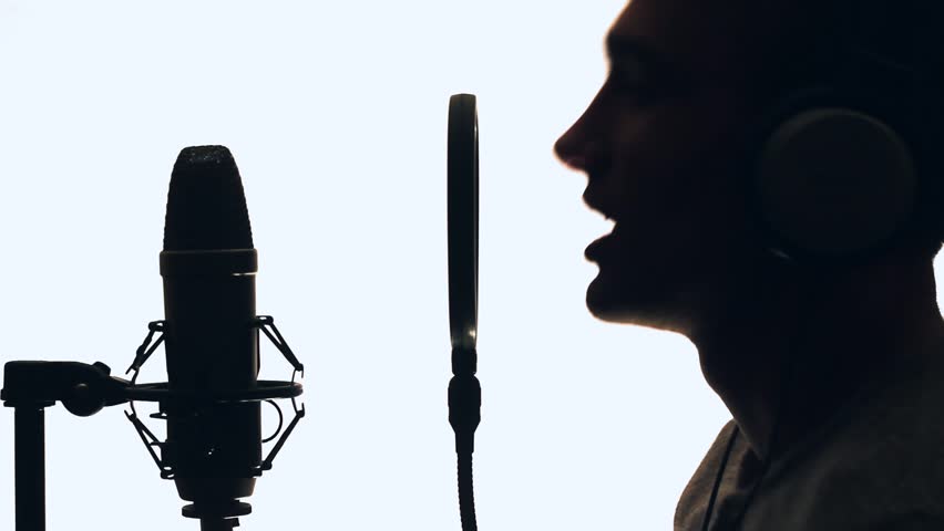 Handsome Guy Singing Into A Microphone Standing Backlit. Recording ...