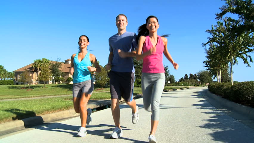 Young Friends Keeping Fit Together Jogging Outdoors On Suburban Roads ...