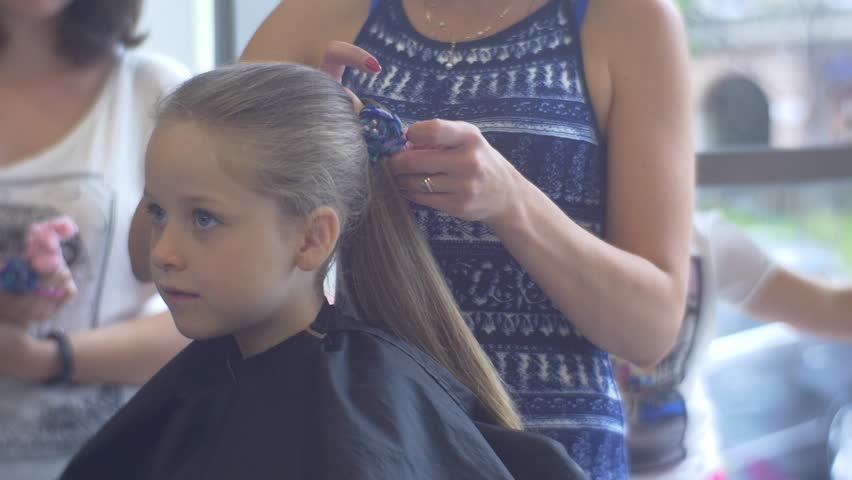 Hairdresser Combs And Dries Blonde Kid's Hairs. Little Girl Iis Sitting ...