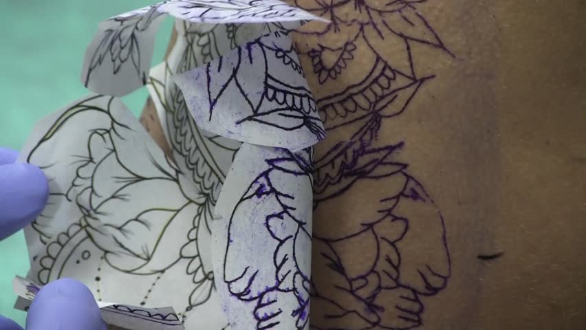 a tattoo artist is tattooing a hip of a young stock footage a tattoo artist is tattooing a hip of a young stock footage