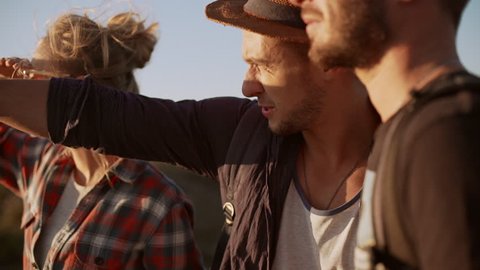 Three friends with map and compass trying to find way in prairie. Close up view in slowmotion
