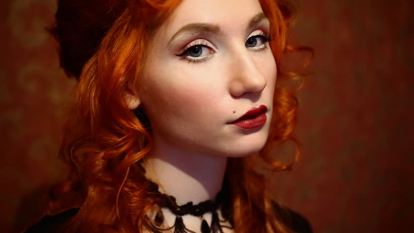 Portrait Of A Woman With Long Red Curly Hair In A Black And Red Dress And Choker On Her Neck