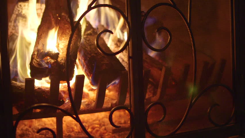 Logs Burning In Vintage Stone Fireplace With Decorative Screen