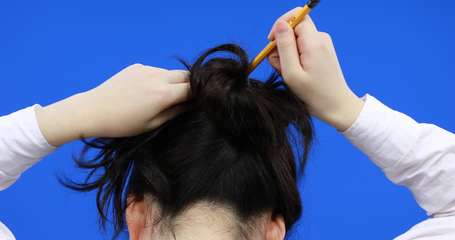 Girl Putting Her Hair Up With Pencil Pencil Bun