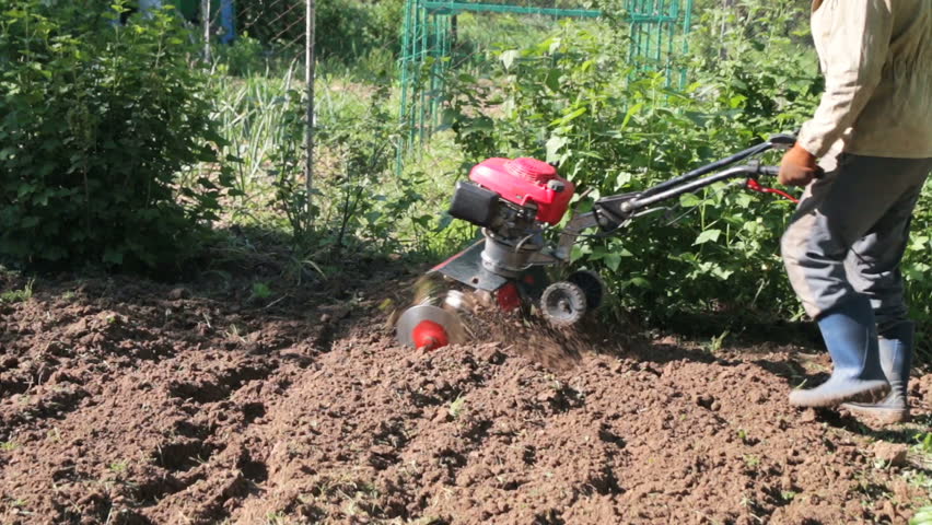 Plowing The Soil With Handheld Machine. Person Working On Own Garden ...