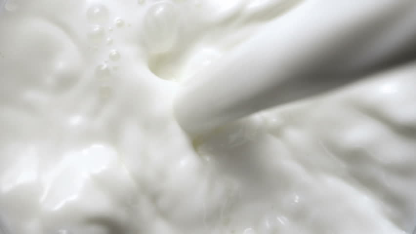 Pouring milk in the glass on black background