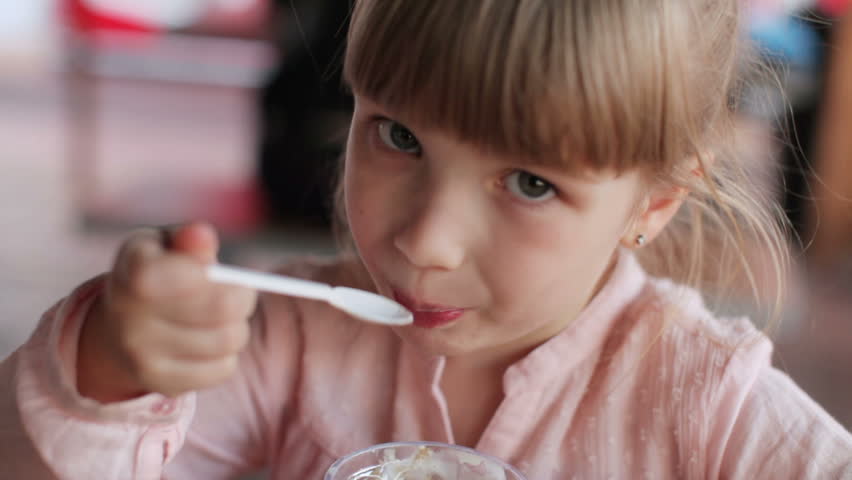 Kid sitting at cafe and eating ice-cream
