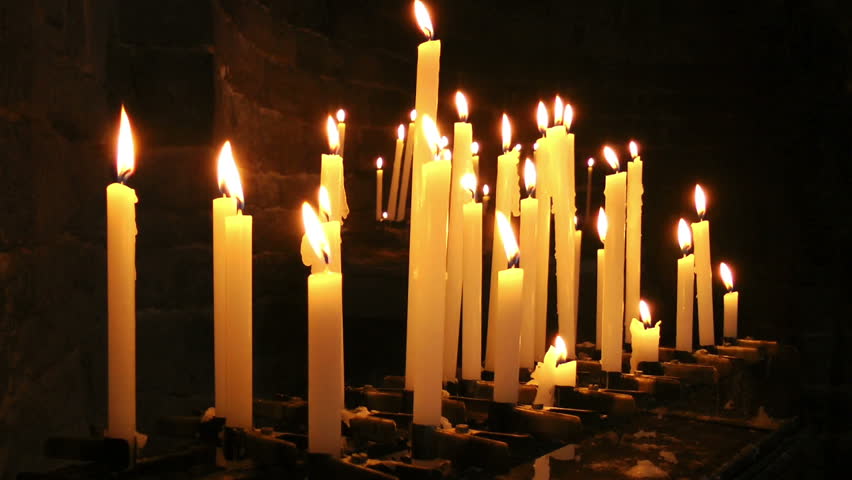 Some Lit Candles, Are Lined Up In Front Of An Altar In A Catholic