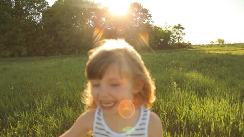 Girl running in field with smile with flare