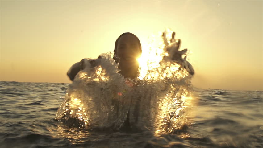 SLOW MOTION: Young woman splashing ocean water with her 