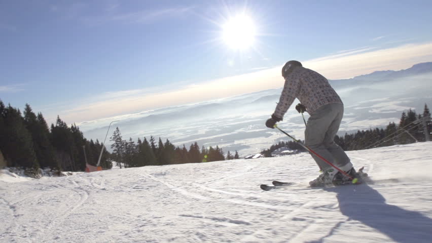 Speed Ramp Rear View Shot Of Skier Carving Down The Ski Slope With Snow Drifting